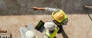 Construction managers standing on the job site and engineers holding a laptop and pointing at something on the job site