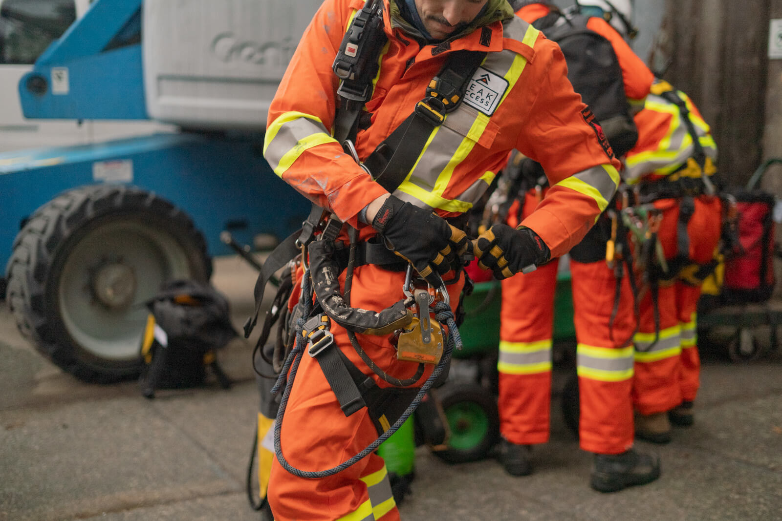 Peak Access employee suits up in reflective coveralls and harness equipped with safety gear